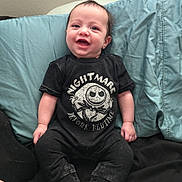Cole is registered to the contest to win money with this photo: baby, child, smiling, sitting, black_clothing, checkered_shoes, couch, pillows, indoor, happy, infant, footwear, cute, young_child, portrait, casual_clothing, comfortable, home, person, black_background