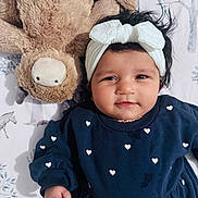 Siya joined the competition — help win amazing prizes! animal_print, baby, bedspread, bow, child, cute, face, hand, headband, hearts_pattern, indoors, infant, lying_down, moose, navy_blue_clothing, plush_toy, portrait, smile, soft_toy, tree_print