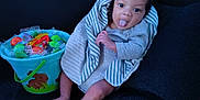 Adonyze joined the competition — help win amazing prizes! baby, child, tongue_out, striped_blanket, bucket, candy, toys, blue_bucket, gray_clothing, sitting, playful, cute, dark_background, indoor, infant, person, smiling, legs, hand, face