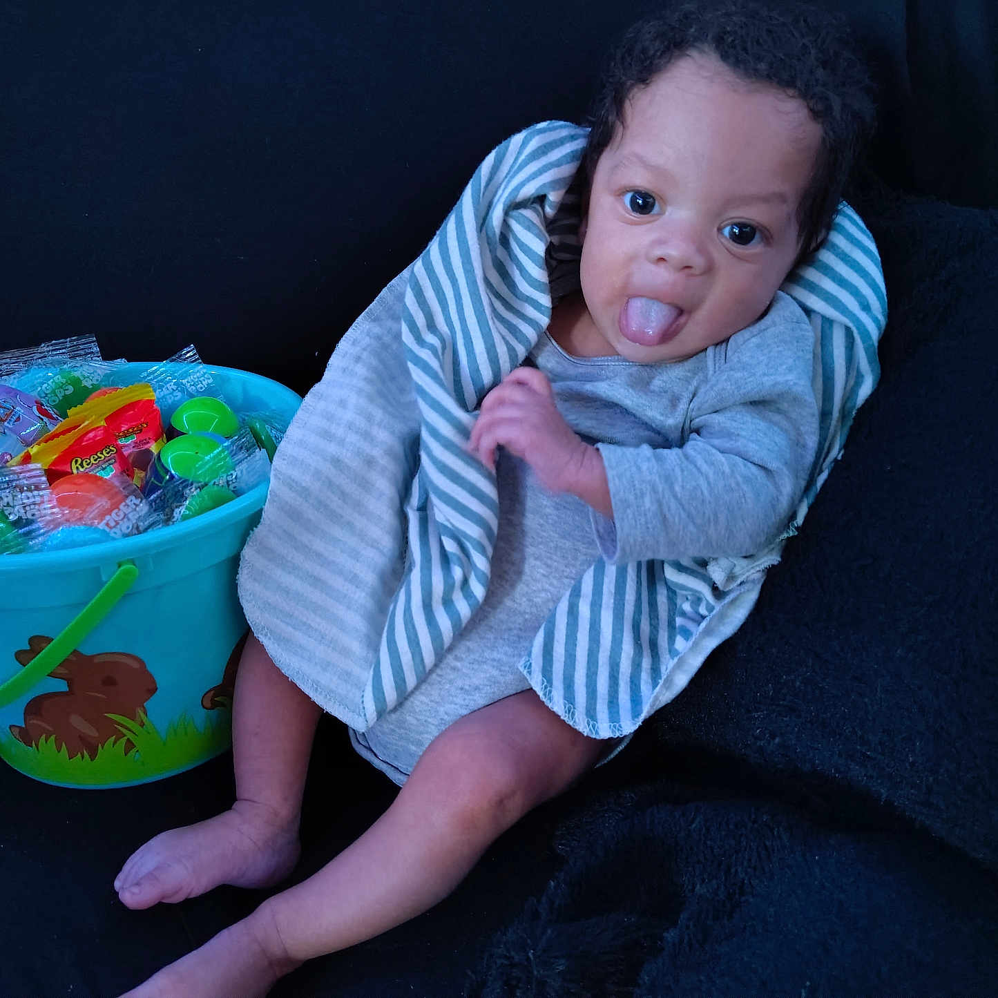 Adonyze joined the competition — help win amazing prizes! baby, blue_bucket, bucket, candy, child, cute, dark_background, face, gray_clothing, hand, indoor, infant, legs, person, playful, sitting, smiling, striped_blanket, tongue_out, toys