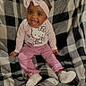 baby, child, smiling, pink_clothing, headband, bow, hello_kitty, sitting, blanket, checkered_pattern, shoes, happy, indoors, cute, portrait, young_child, infant, cozy, clothing, person