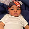 Roderick is registered to the contest to win money with this photo: baby, blanket, child, clothing, comfort, expression, eyes, face, football_pattern, head_wrap, headwear, indoors, infant, lying_down, portrait, resting, skin, toddler, white_onesie, young_child