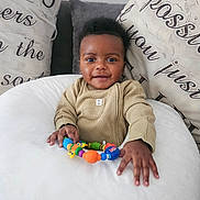 Ezra joined the competition — help win amazing prizes! baby, child, clothing, colorful, cozy, cushion, cute, face, hand, happy, home, indoor, infant, person, pillow, playful, portrait, seated, smile, toy