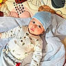 baby, infant, child, beanie, pajamas, blanket, quilt, pattern, fabric, soft_texture, indoor, laying_down, cute, portrait, face, wide_eyes, expression, cozy, clothing, hands