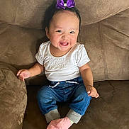 Lydia joined the competition — help win amazing prizes! baby, child, smiling, sitting, portrait, indoors, couch, furniture, purple_bow, white_shirt, blue_jeans, pink_socks, happy, infant, face, arms, hands, home, fashion, photography
