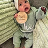 baby, blanket, child, couch, cozy, cute, expression, fabric, feet, green_clothing, hand, headband, indoors, infant, newborn, person, portrait, sitting, soft_texture, wooden_sign