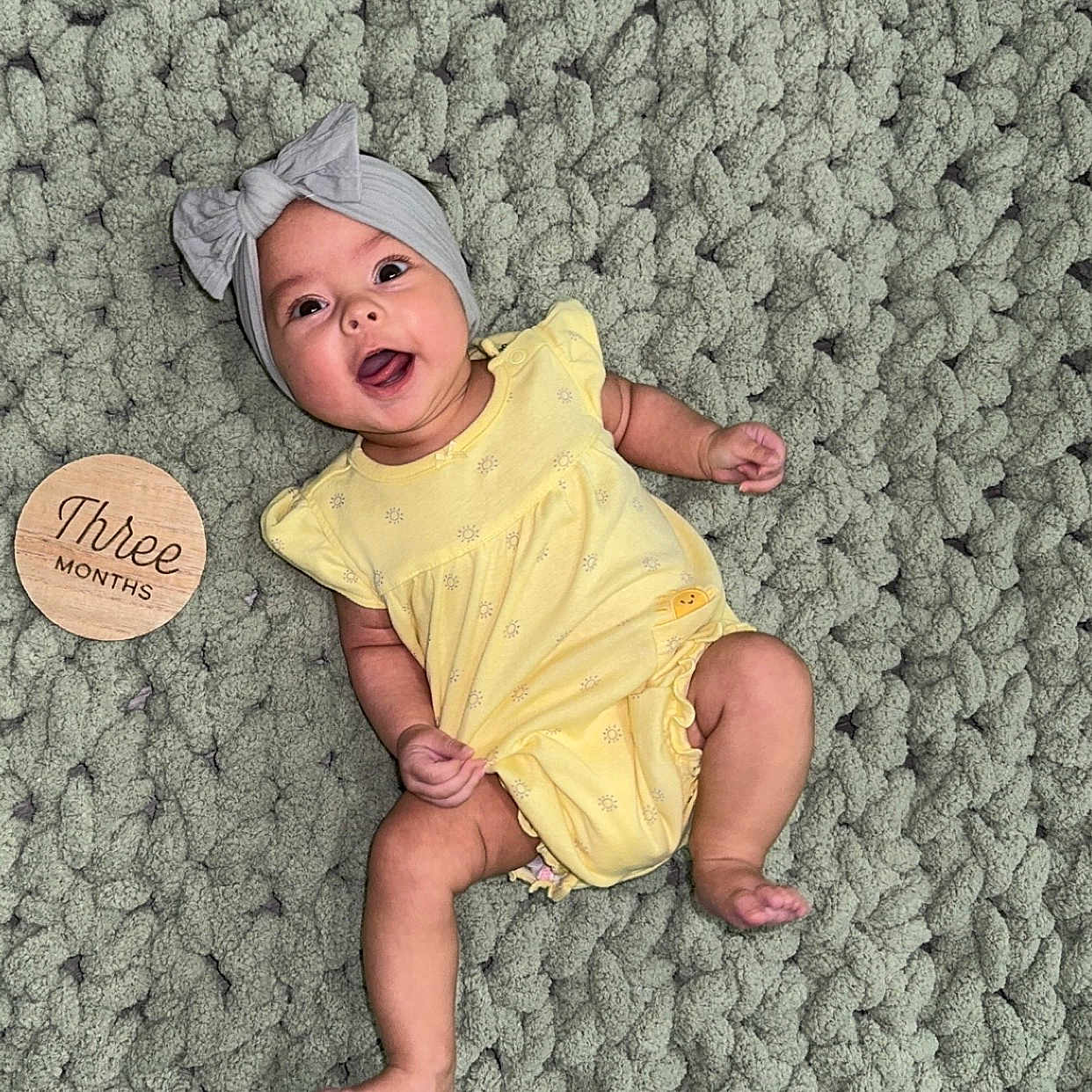 Hyacinth joined the competition — help win amazing prizes! baby, infant, yellow_clothing, headband, smiling, lying_down, textile, blanket, wooden_sign, three_months, cute, happy, face, child, small_person, indoors, soft_texture, playful, portrait, baby_girl