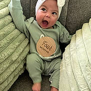Hyacinth is registered to the contest to win money with this photo: baby, blanket, bow, child, couch, cozy, cute, expression, four_months, green_outfit, happy, headband, indoor, infant, person, portrait, sitting, smiling, soft_texture, young_child