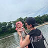 baby, adult, lake, water, trees, outdoor, nature, smiling, hat, tattoo, chair, person, happy, summer, sky, cloudy, family, holding, casual, relaxation