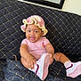 baby, child, smiling, pink_hat, striped_onesie, shoe, couch, black_quilted_couch, cute, happy, indoor, playful, sitting, tongue_out, crocheted_hat, footwear, infant, person, portrait, home