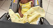 Kyasia joined the competition — help win amazing prizes! baby, sleeping, stroller, blanket, yellow_clothing, indoor, tile_floor, pink_cushion, black_chair, red_rug, peaceful, infant, child, person, cute, cozy, portrait, resting, curly_hair, car_seat