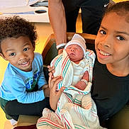 Noah joined the competition — help win amazing prizes! newborn, baby, child, siblings, hospital, blanket, smile, family, holding, striped_blanket, arm, person, curly_hair, hat, clothing, chair, happy, indoor, portrait, bonding