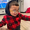 Hanzel Aquino is registered to the contest to win money with this photo: child, toddler, smiling, glasses, hood, portrait, indoor, home, television, tennis, sports, red, black, checkered, clothing, fashion, standing, wood_floor, furniture, happy