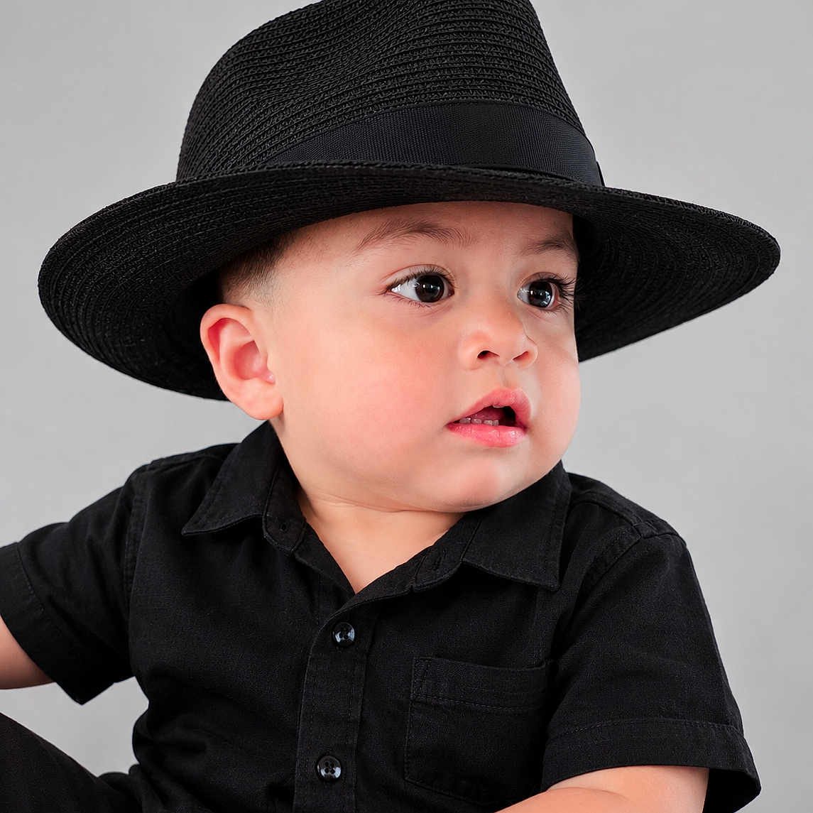 Hanzel Aquino is registered to the contest to win money with this photo: baby, child, portrait, fedora, hat, black_clothing, shirt, studio, gray_background, sitting, face, eyes, serious_expression, open_mouth, looking_away, fashion, closeup, indoor, photography, adorable