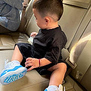 Hanzel Aquino is registered to the contest to win money with this photo: child, toddler, boy, car, car_interior, leather_seat, seated, black_shirt, black_shorts, sneakers, blue_shoes, bottle, short_hair, side_profile, passenger, vehicle, seatbelt, portrait, indoors, casual