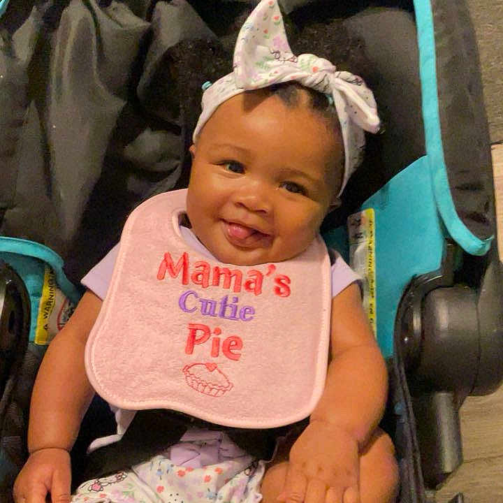 Julianna Benton joined the competition — help win amazing prizes! accessory, baby, baby_girl, bib, child, clothing, comfort, cute, expression, happy, headband, indoor, infancy, infant, person, portrait, sitting, smiling, stroller, young_child