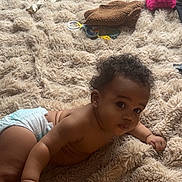 Ysmaël a rejoint le concours — aidez-le/la à gagner de superbes lots ! baby, diaper, carpet, toy, blanket, curly_hair, child, indoor, floor, playtime, infant, soft_texture, crawling, cute, person, home, relaxed, looking_up, skin, hand