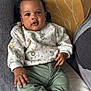 Ysmaël participe au concours pour gagner de l'argent avec cette photo : baby, child, infant, couch, sweater, pants, animal_print, curly_hair, indoors, cushion, blanket, portrait, sitting, hand, feet, comfortable, cute, looking_at_camera, expression, cozy
