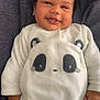 baby, blanket, child, clothing, cozy, cute, dark_background, face, hand, happy, indoors, infant, infant_fashion, lying_down, newborn, onesie, panda_design, portrait, smiling, soft_texture