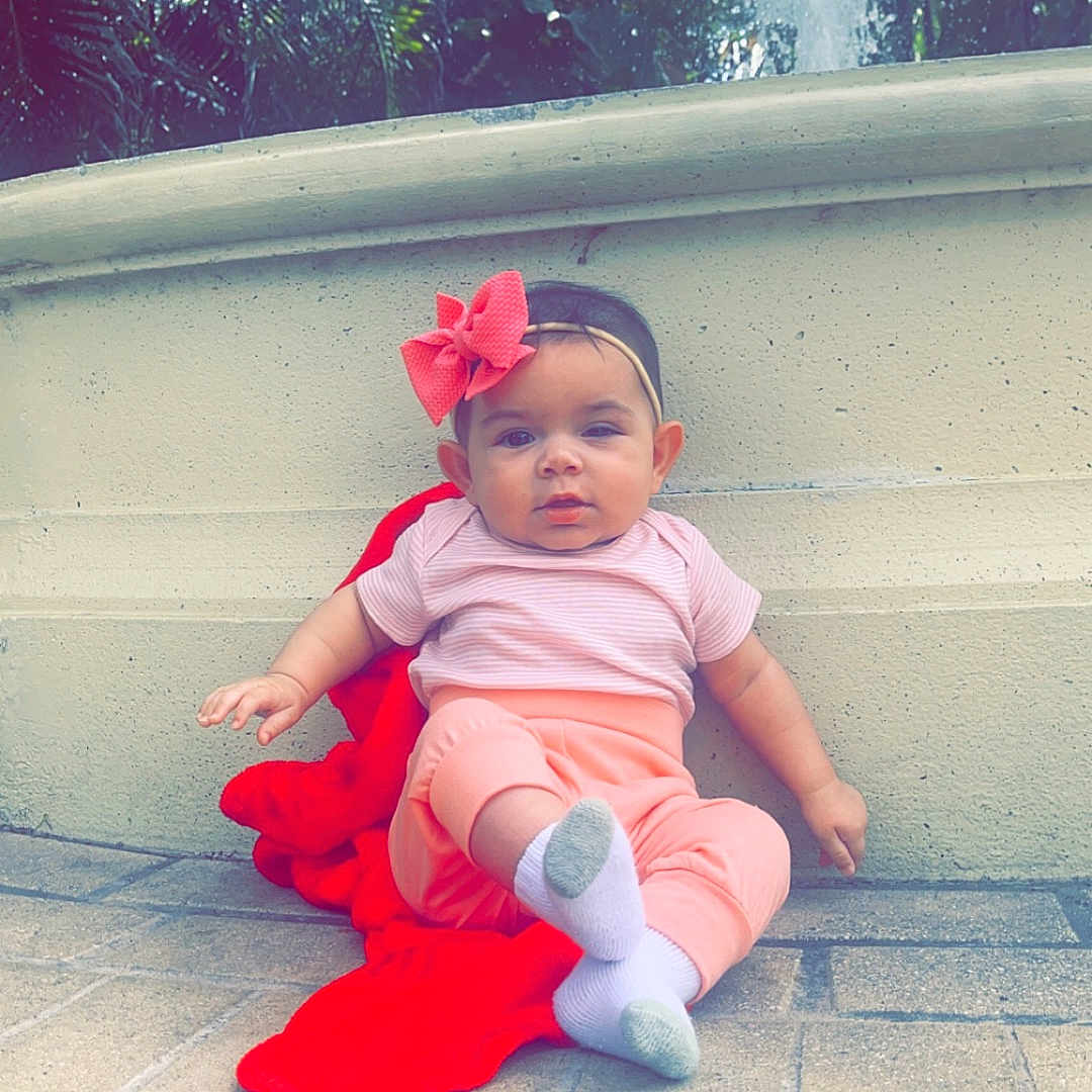 Reina joined the competition — help win amazing prizes! baby, bench, child, cute, daylight, fountain, greenery, headband, nature, outdoor, pants, person, pink_bow, portrait, red_blanket, relaxing, sitting, socks, stone, tshirt