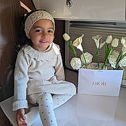 Seyana participe au concours pour gagner de l'argent avec cette photo : child, girl, smile, knitwear, headband, tights, polka_dot, flowers, dior, flower_arrangement, indoor, table, happy, cute, portrait, sitting, cozy, warm_lighting, decor, young