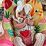 baby, baby_chair, child, clothing, colorful_chair, comfort, cute, hands_clasped, headband, indoor, infant, knitted_socks, looking_at_camera, pacifier, playful, portrait, seated, soft_lighting, tiger_design, white_bow