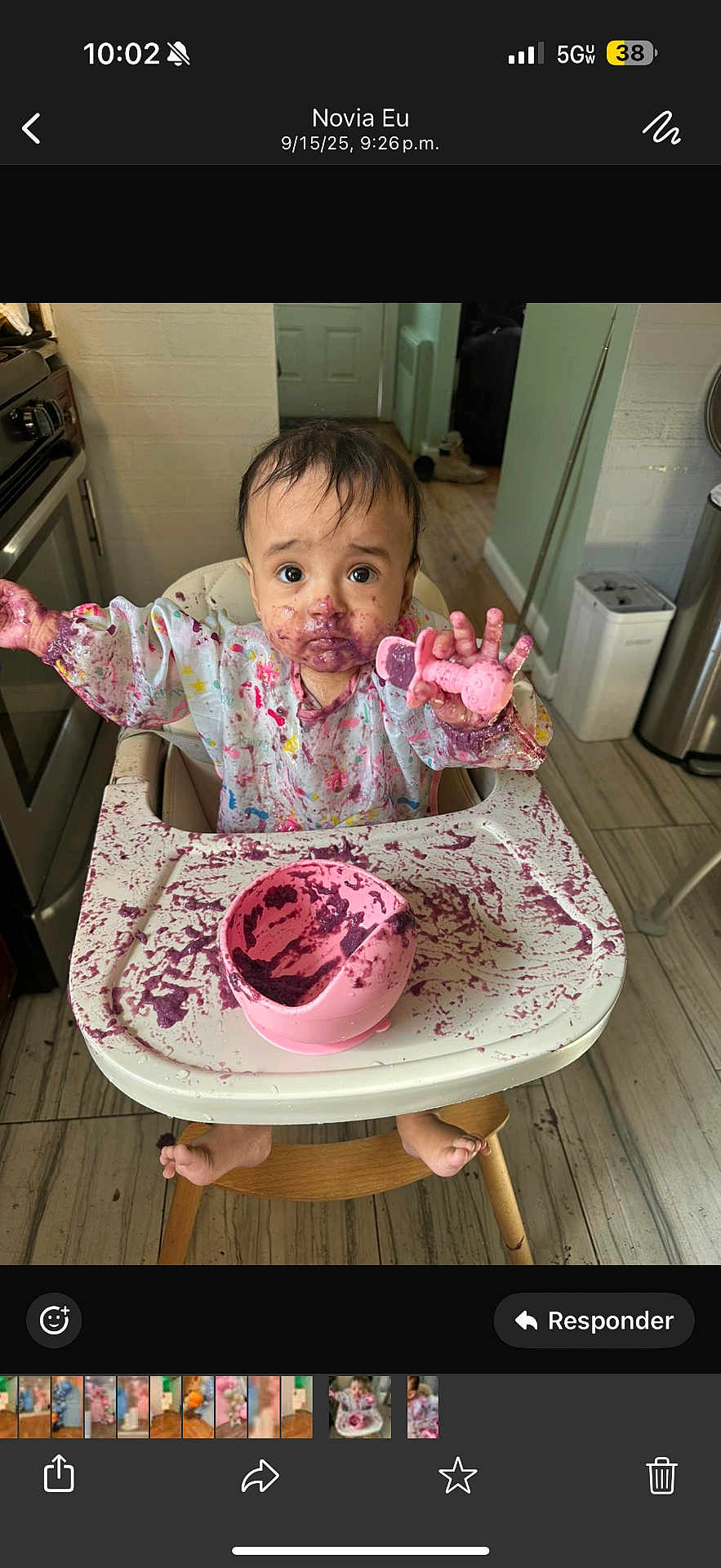 Addison is registered to the contest to win money with this photo: baby, high_chair, messy, food, purple, teether, kitchen, floor, wood, plastic_bowl, child, foot, sitting, face, clothing, expression, curious, indoor, table, tray