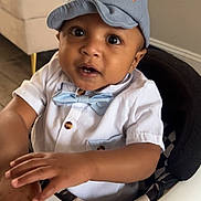 Kyron is registered to the contest to win money with this photo: baby, child, infant, blue_cap, bow_tie, white_shirt, baby_walker, hands, face, eyes, indoor, furniture, floor, cute, portrait, smiling, seated, toy, curious, expression