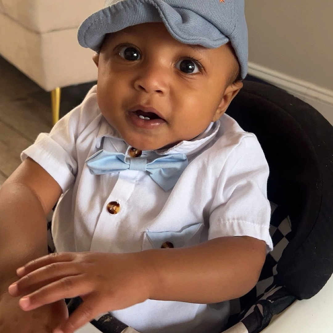 Kyron is registered to the contest to win money with this photo: baby, baby_walker, blue_cap, bow_tie, child, curious, cute, expression, eyes, face, floor, furniture, hands, indoor, infant, portrait, seated, smiling, toy, white_shirt
