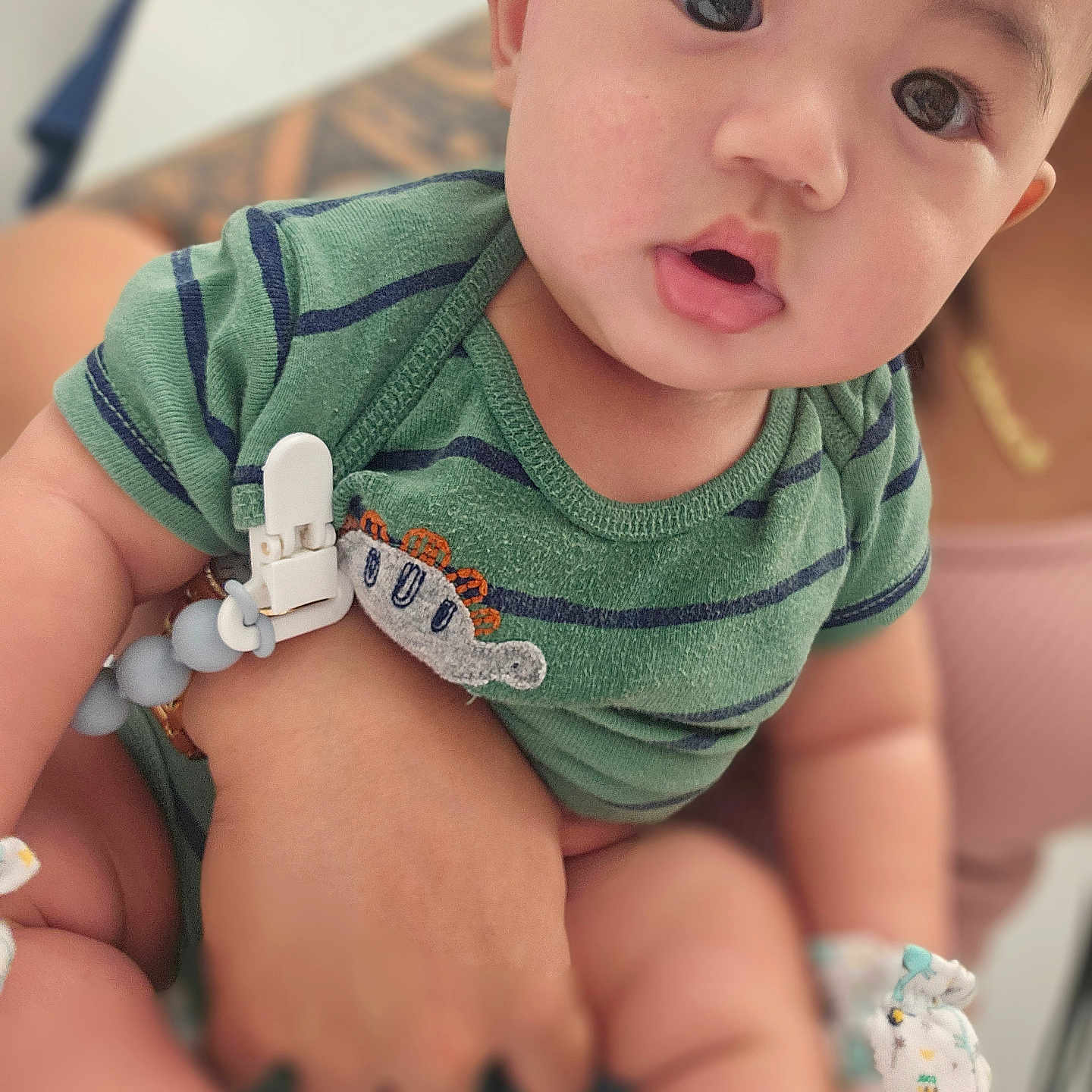 Kamu joined the competition — help win amazing prizes! baby, child, infant, face, eyes, green_clothing, striped, onesie, hand, person, holding, cute, expression, indoors, soft_light, closeup, skin, portrait, young, human