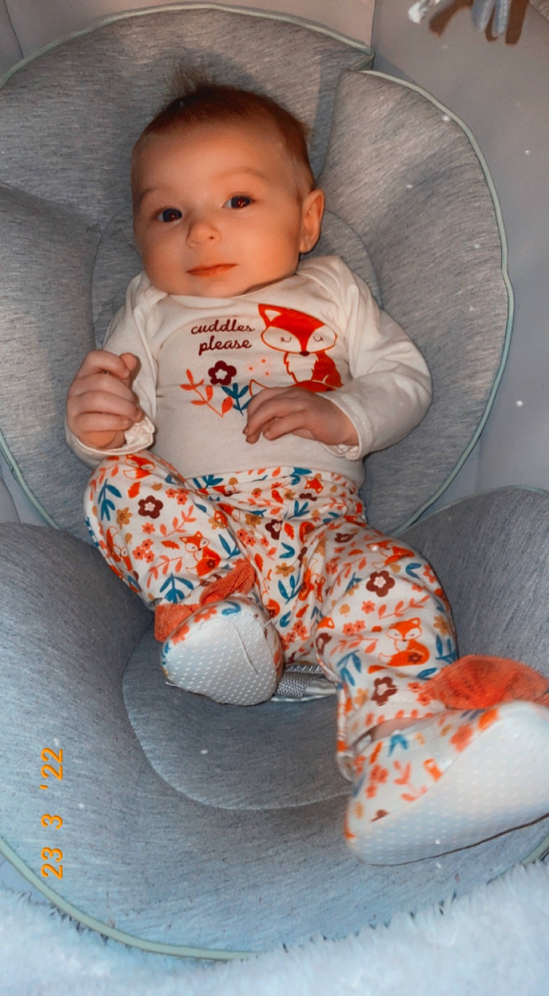 Gracelyn is registered to the contest to win money with this photo: arm, baby, baby_toddler_clothing, cheek, child, comfort, eye, face, flooring, head, knee, linens, orange, pattern, person, sitting, skin, sleeve, sock, textile