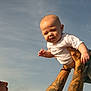 baby, child, tattoo, adult, sky, outdoor, person, holding, joyful, happy, face, arm, expression, casual, daylight, fun, playful, clothing, shorts, tshirt