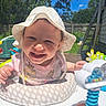 baby, child, smiling, sunhat, outdoor, toy, playtime, cushion, polka_dot, shirt, princess, face, happy, sunny, backyard, grass, tree, fence, ladder, person