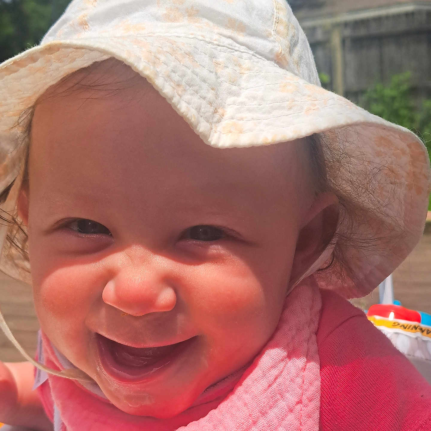 Serena is registered to the contest to win money with this photo: baby, child, smiling, hat, pink_bib, outdoor, sunlight, happy, face, headwear, infant, closeup, portrait, cute, young_child, baby_clothing, daylight, expression, skin, person