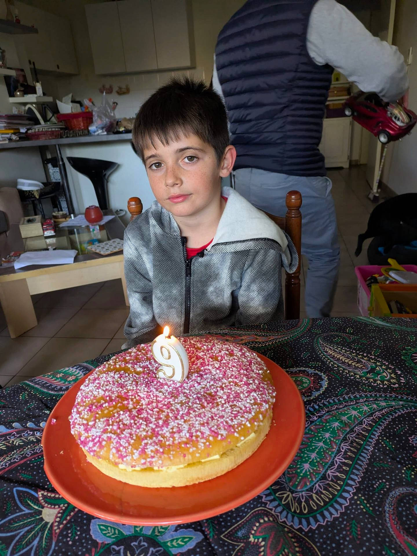 Nathan a rejoint le concours — aidez-le/la à gagner de superbes lots ! adult, birthday_cake, boy, cake, candle, celebration, chair, child, clothing, face, home, indoor, kitchen, lighting, person, plate, sprinkles, sweater, table, toy_car