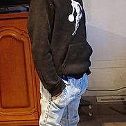 Nathan a rejoint le concours — aidez-le/la à gagner de superbes lots ! boy, cabinet, casual_clothing, child, expression, floor_tiles, furniture, hands_in_pockets, home_interior, hoodie, indoor, jeans, looking_away, portrait, room, side_view, socks, standing, television, young_person