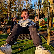 Nathan a rejoint le concours — aidez-le/la à gagner de superbes lots ! active, autumn, casual_clothing, child, daylight, fun, grass, happy, outdoor, park, person, play, playground, recreation, smiling, sneakers, sunlight, swing, tongue_out, trees