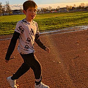 Nathan participe au concours pour gagner de l'argent avec cette photo : boy, child, running, outdoor, track, grass, sunlight, shadow, sky, casual_clothing, sneakers, long_sleeves, tshirt, park, daytime, nature, motion, youth, active, recreation