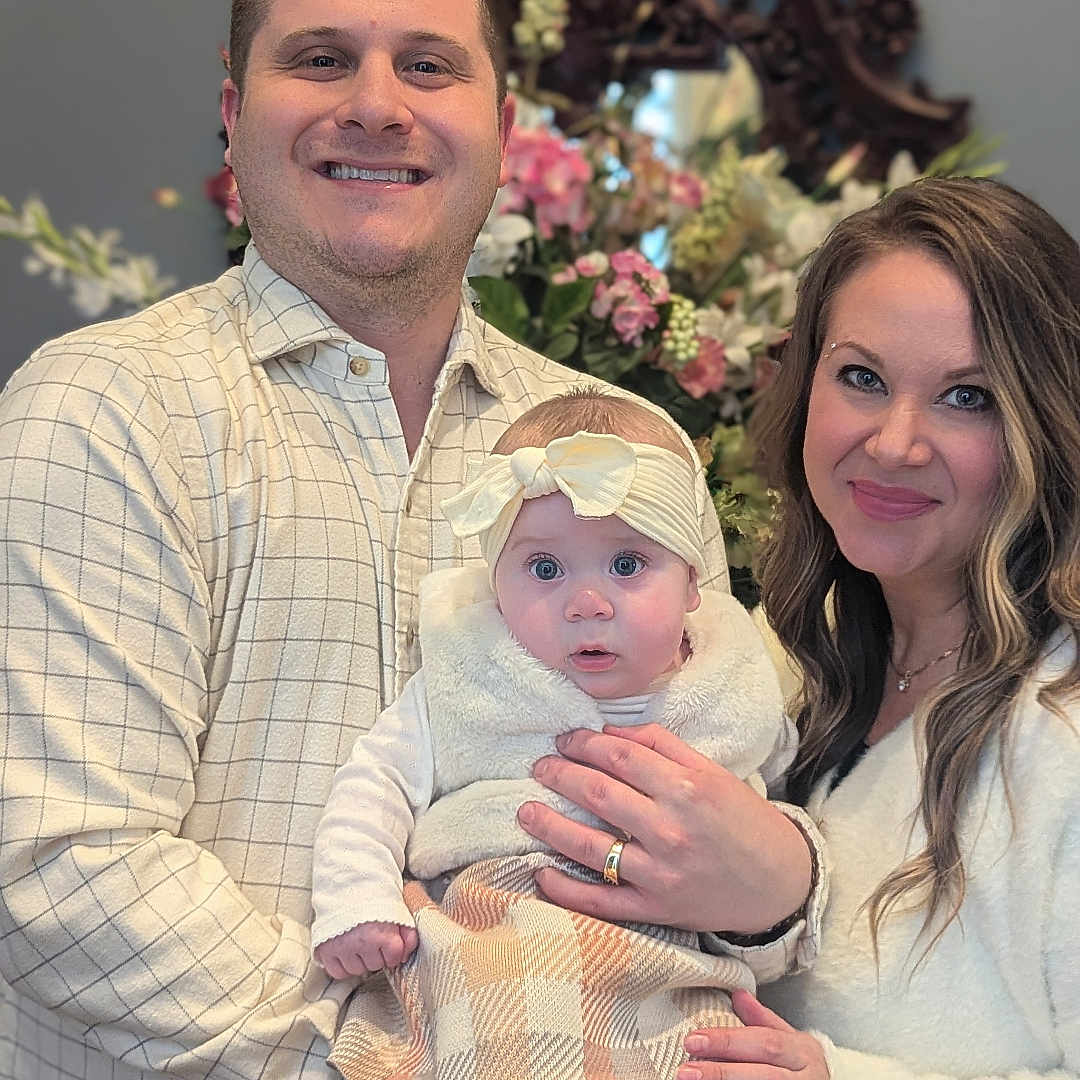 Lillian is registered to the contest to win money with this photo: adult, baby, clothing, face, female, flower, flowerarrangement, flowerbouquet, head, male, man, newborn, pants, people, person, photography, plant, portrait, shirt, woman