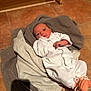 newborn, baby, infant, blanket, towel, white_clothing, orange_booties, floor, tile, indoors, person, laying_down, cute, small, young_child, face, head, cozy, resting, soft