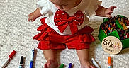 Carmen is registered to the contest to win money with this photo: baby, child, infant, red_clothing, white_clothing, markers, crayons, colorful, sitting, blanket, milestone, six_months, sign, cute, indoors, art_supplies, person, feet, head, playful