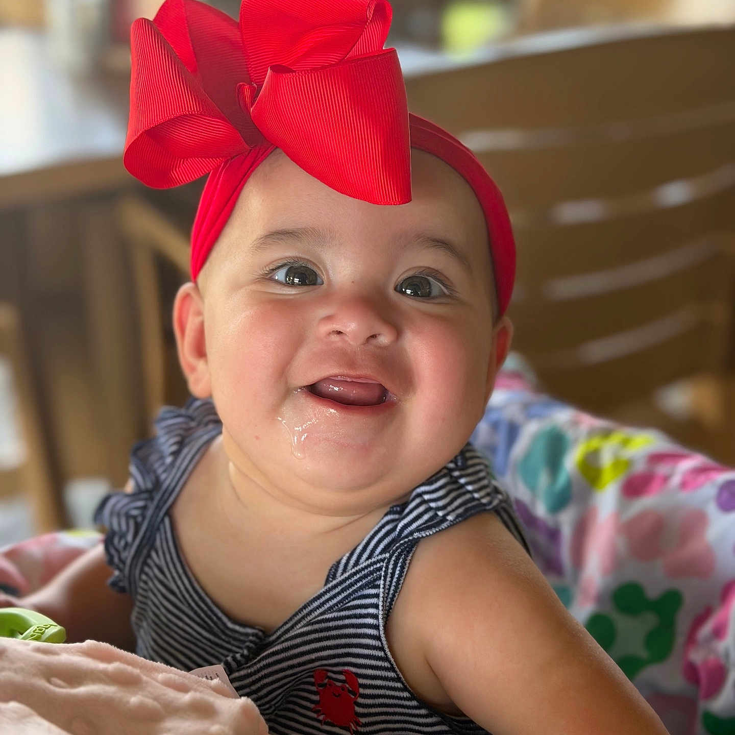 Carmen joined the competition — help win amazing prizes! baby, child, red_bow, drool, striped_clothing, smiling, happy, portrait, close_up, indoor, soft_lighting, colorful_blanket, cute, infant, face, headwear, person, cheerful, young, seated