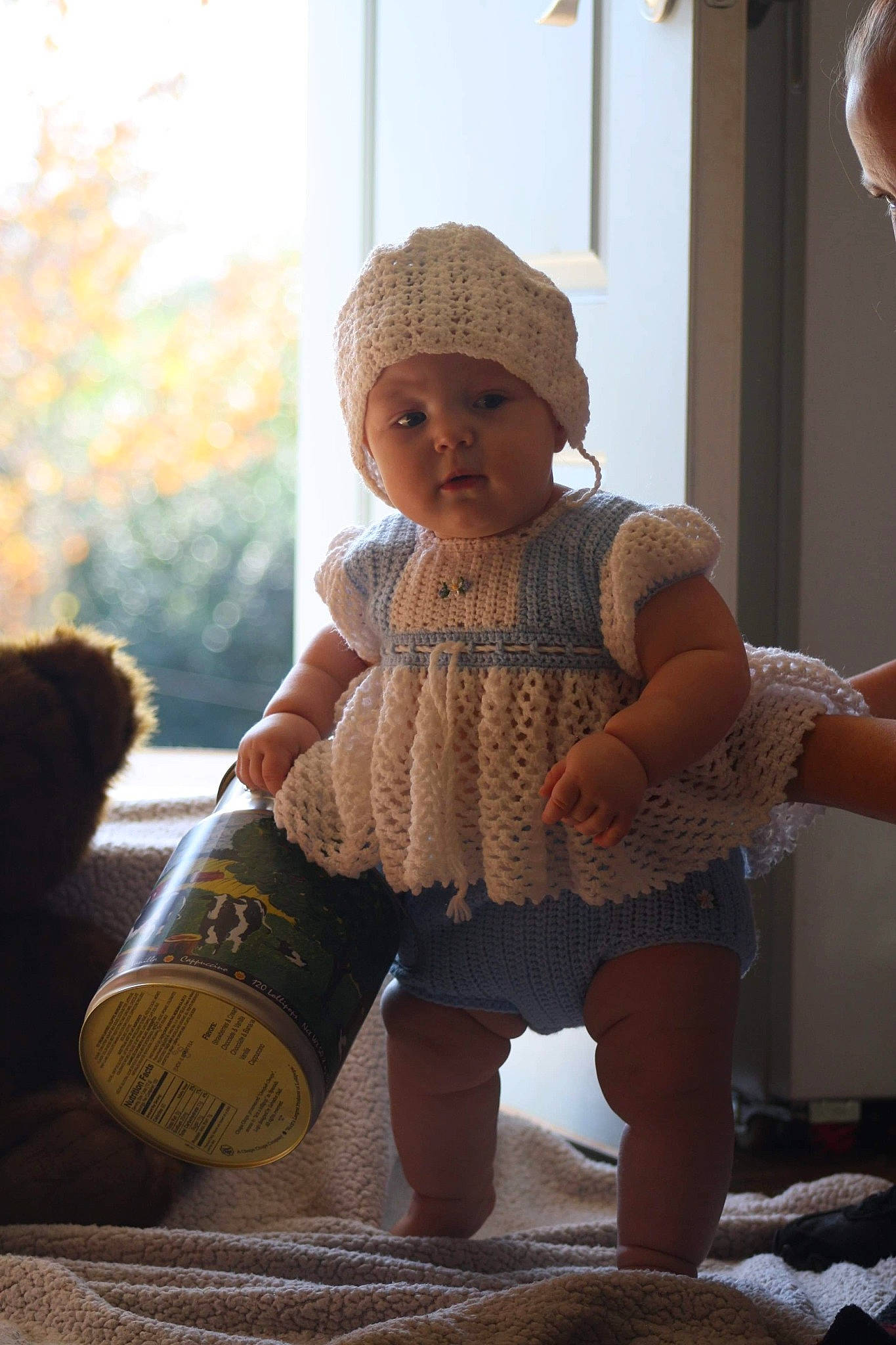 Savanna is registered to the contest to win money with this photo: baby, baby_products, bonnet, bottle, child, hat, headgear, knit_cap, knitting, person, product, room, sitting, skin, toddler, toy, vacation, wool
