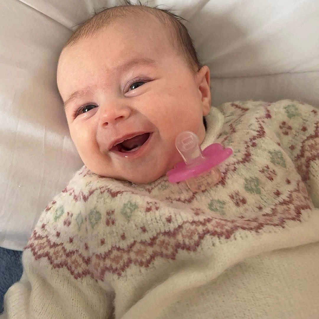 Inaya a rejoint le concours — aidez-le/la à gagner de superbes lots ! baby, bed, blanket, bodypart, clothing, cushion, face, furniture, happy, head, homedecor, knitwear, laughing, newborn, person, photography, portrait, quilt, smile, sweater