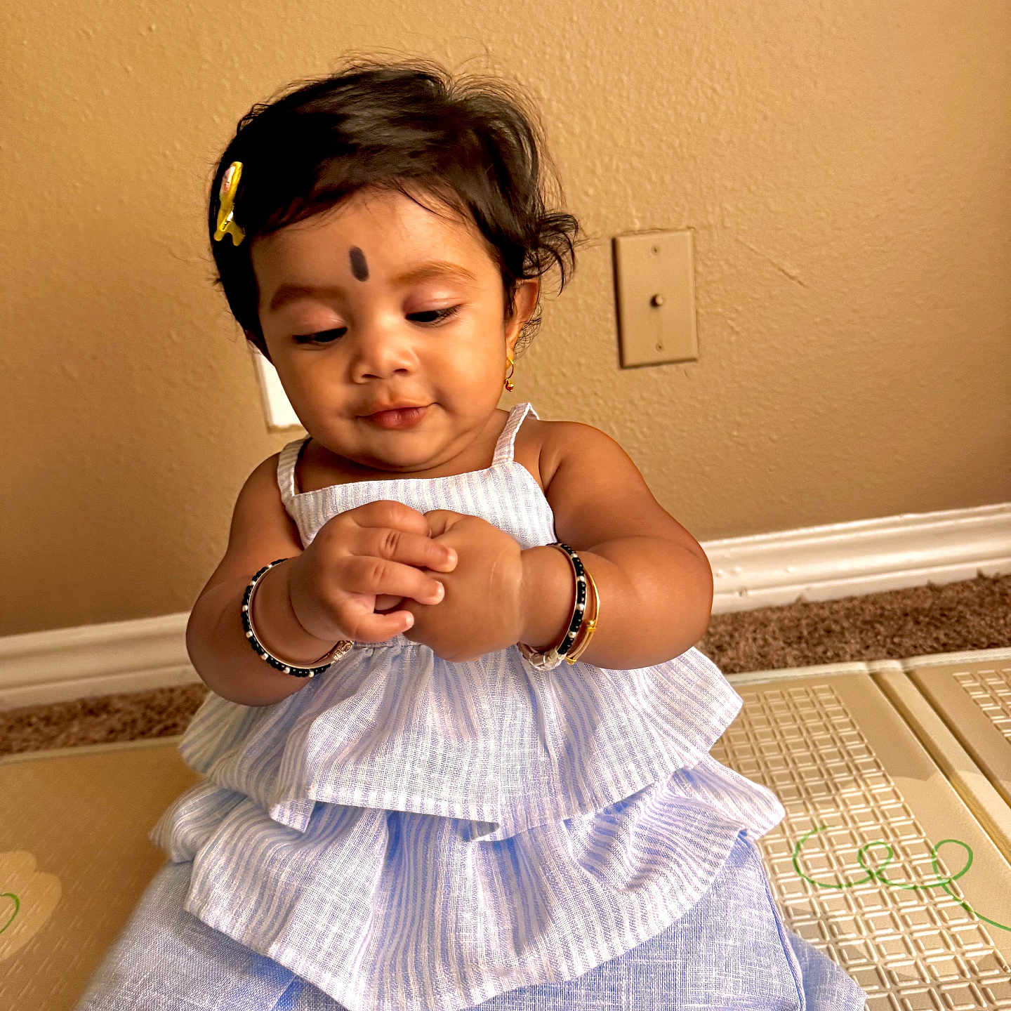 Parnika joined the competition — help win amazing prizes! adorable, baby, bracelet, child, curly_hair, cute, dress, expression, floor, focused, girl, hair_clip, indoor, infant, light_switch, mat, pattern, sitting, skin, wall