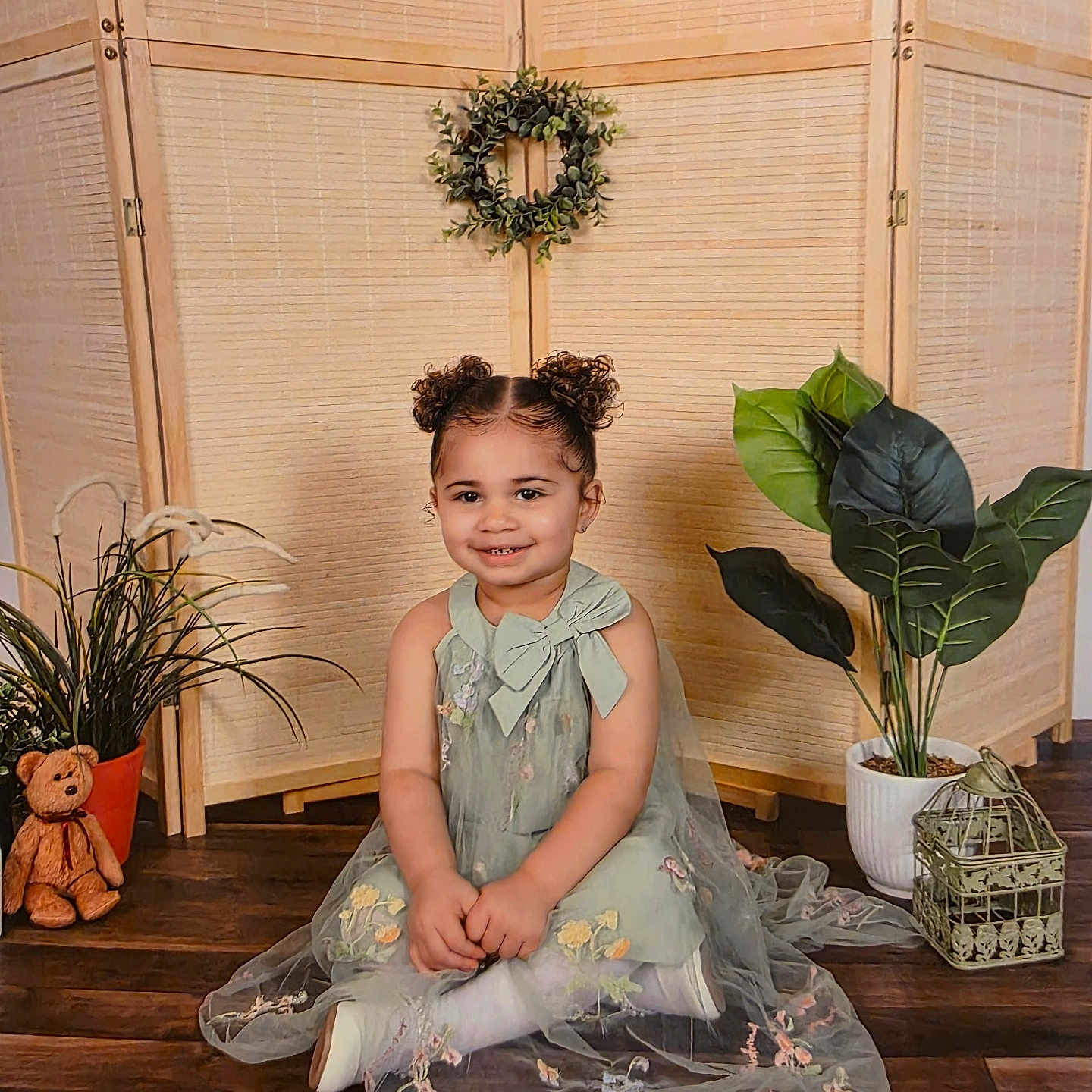 Satori is registered to the contest to win money with this photo: bow, child, curly_hair, cute, decor, dress, floor, girl, happy, home, indoor, plant, portrait, potted_plant, screen, sitting, smiling, teddy_bear, wooden_floor, wreath