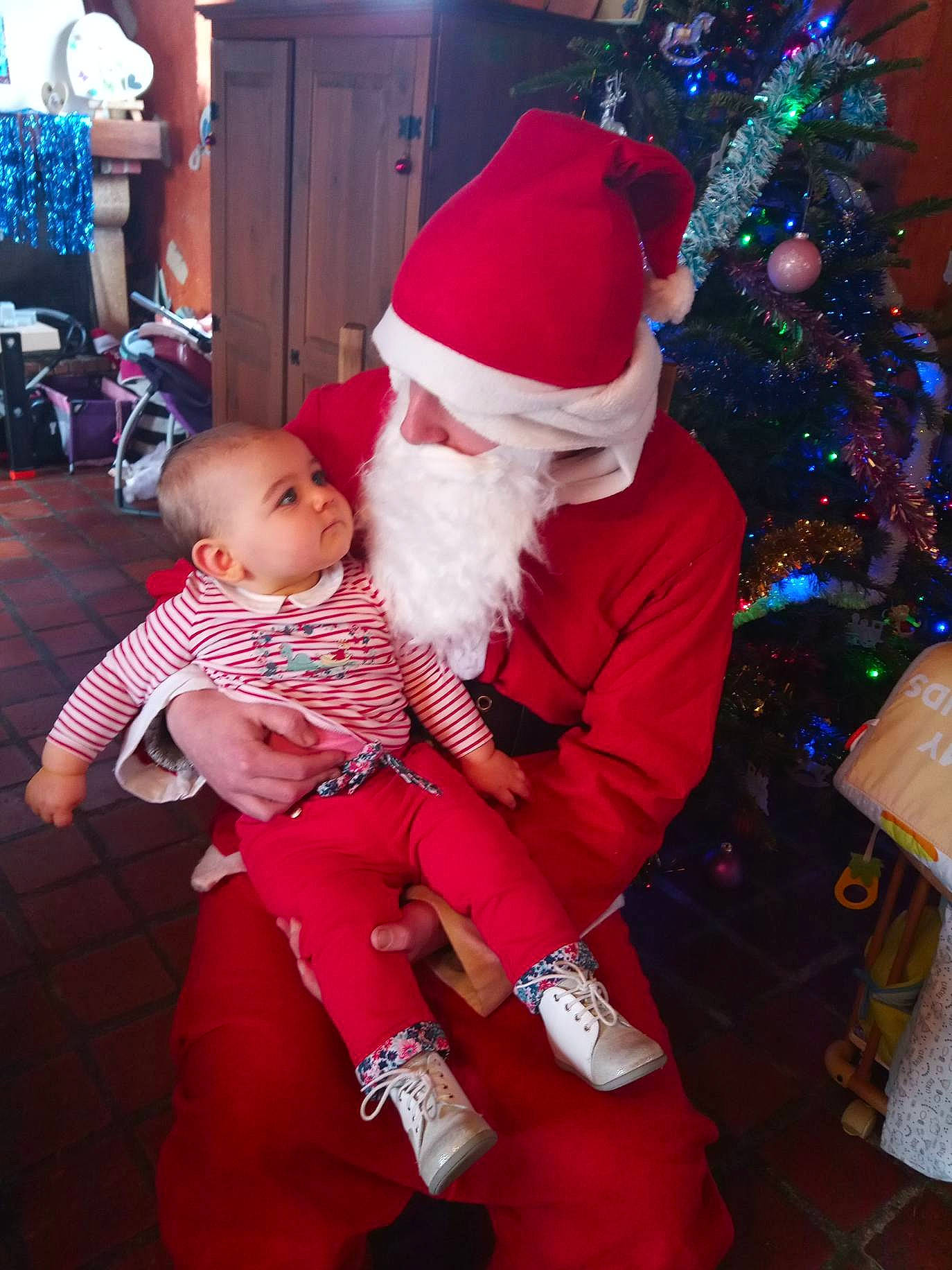 Talya participe au concours pour gagner de l'argent avec cette photo : baby, child, christmas, christmas_decoration, christmas_eve, christmas_tree, costume, event, fictional_character, happy, holiday, human_body, lap, leg, person, santa_claus, smile, toddler, tradition, tree