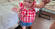 Kelly Kay joined the competition — help win amazing prizes! adult_hand, baby, blanket, brown_shoes, cabinet, child, couch, denim_skirt, floor, footwear, hand_holding, home, indoor, living_room, microwave, person, red_checkered, toddler, walking, wood_floor