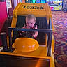 arcade, baby, carpet, child, colorful, cute, entertainment, fun, game_machine, happy, indoor, kid, person, playful, seat, steering_wheel, tonka, toy_truck, vehicle, yellow