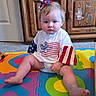 Kelly Kay joined the competition — help win amazing prizes! baby, carpet, cartoon_stickers, casual, child, colorful_mat, cute, floor_mat, foam_puzzle, furniture, hair_accessory, home, indoor, patriotic_clothing, person, serious_expression, sitting, toddler, wooden_cabinet, young_child